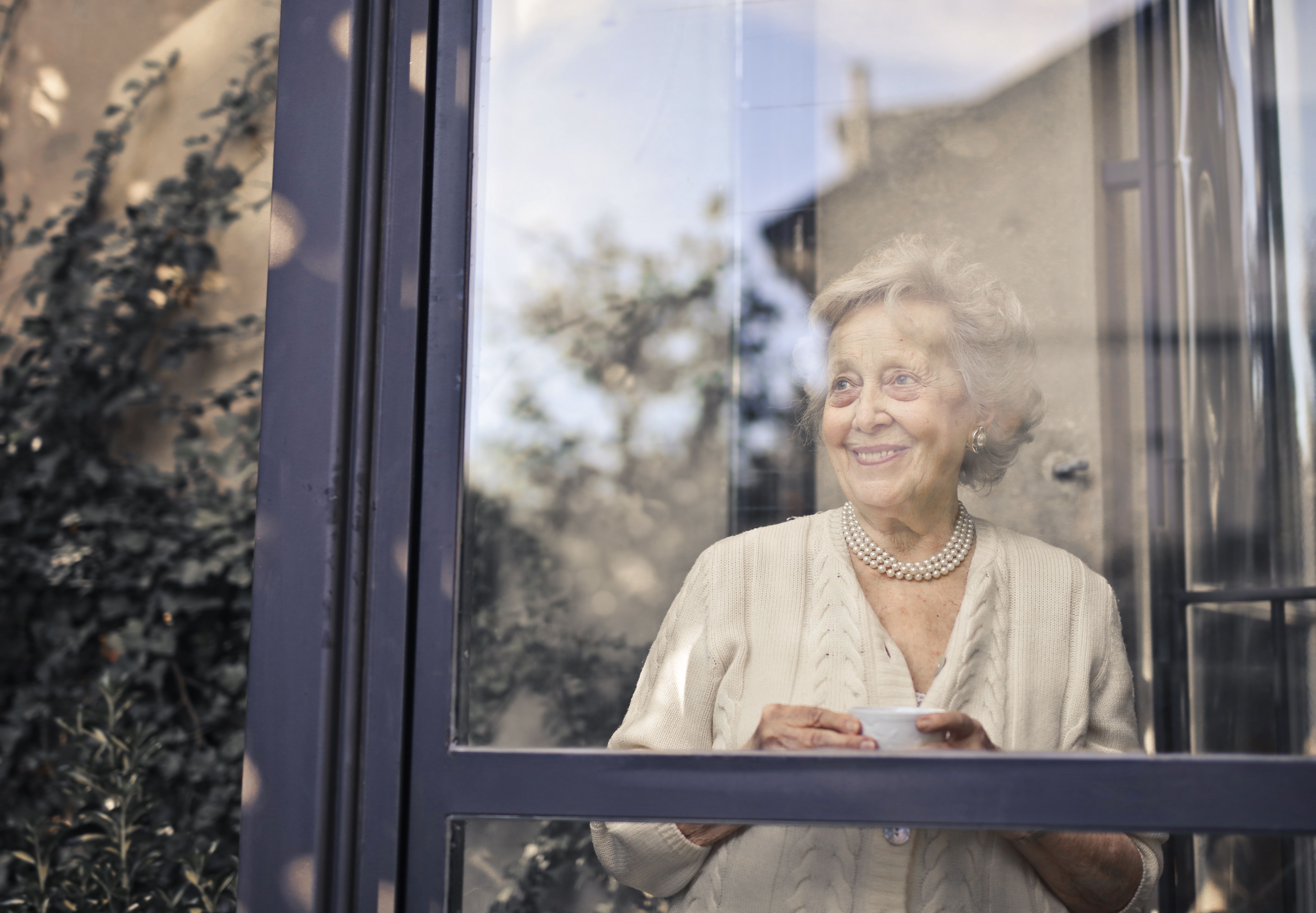 Woman Smiling Through Window | Seattle Elder Law Guide to Long-Term Care Options